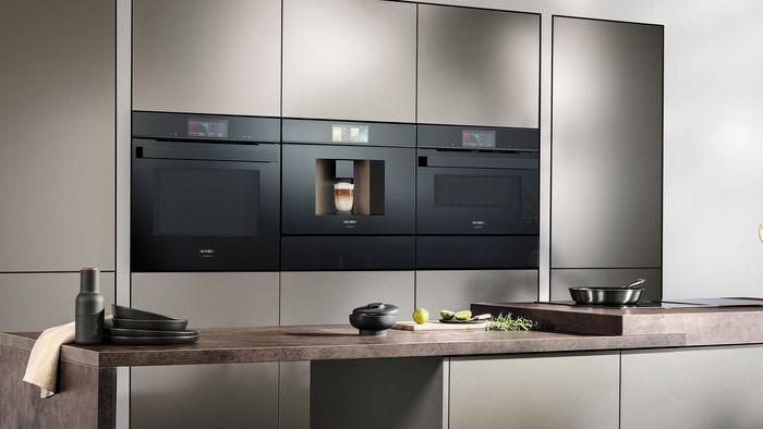 Moderne Küche mit eingebauten schwarzen Geräten, Holzarbeitsplatte und minimalistischem Design.