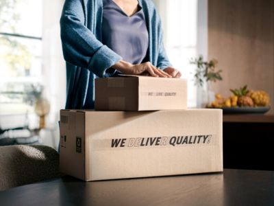 Cajas de retención de la persona con texto "Ofrecemos calidad", en un entorno de hogar con frutas.