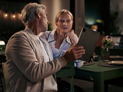 Pareja más vieja mirando la tableta juntos, ambiente íntimo de noche con velas.
