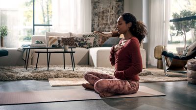 Una mujer joven practica yoga en su salón