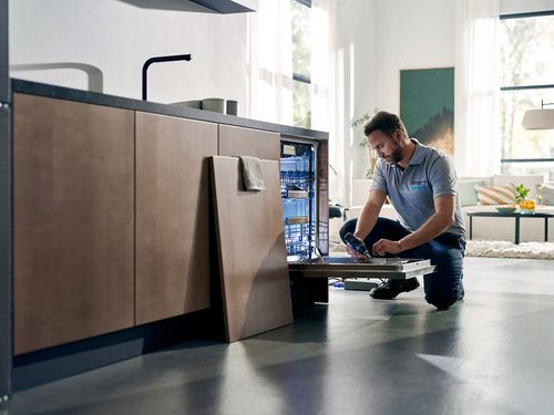 Person, der arbejder på en opvaskemaskine i et moderne køkken.  