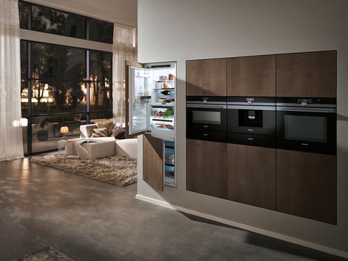 Cozinha moderna com aparelhos elegantes, sala de estar aberta e grandes janelas com vista para o cenário exterior. 