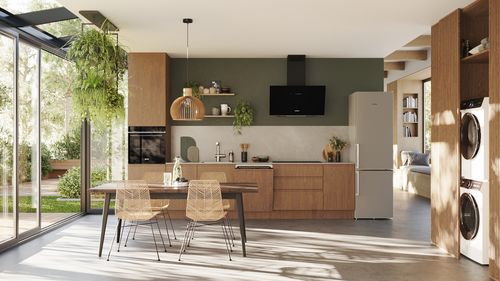 Moderne, helle Küche mit Esstisch, Stühlen und Pflanzen, durchflutet von Tageslicht.