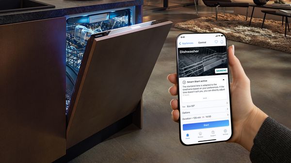 HomeConnect-appen åbnet i en telefon ved siden af en opvaskemaskine